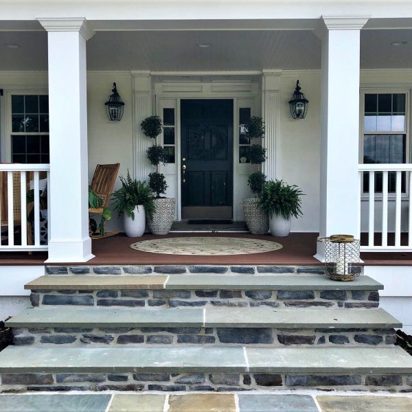 Stone steps leading up to the front door of a white house with porch columns