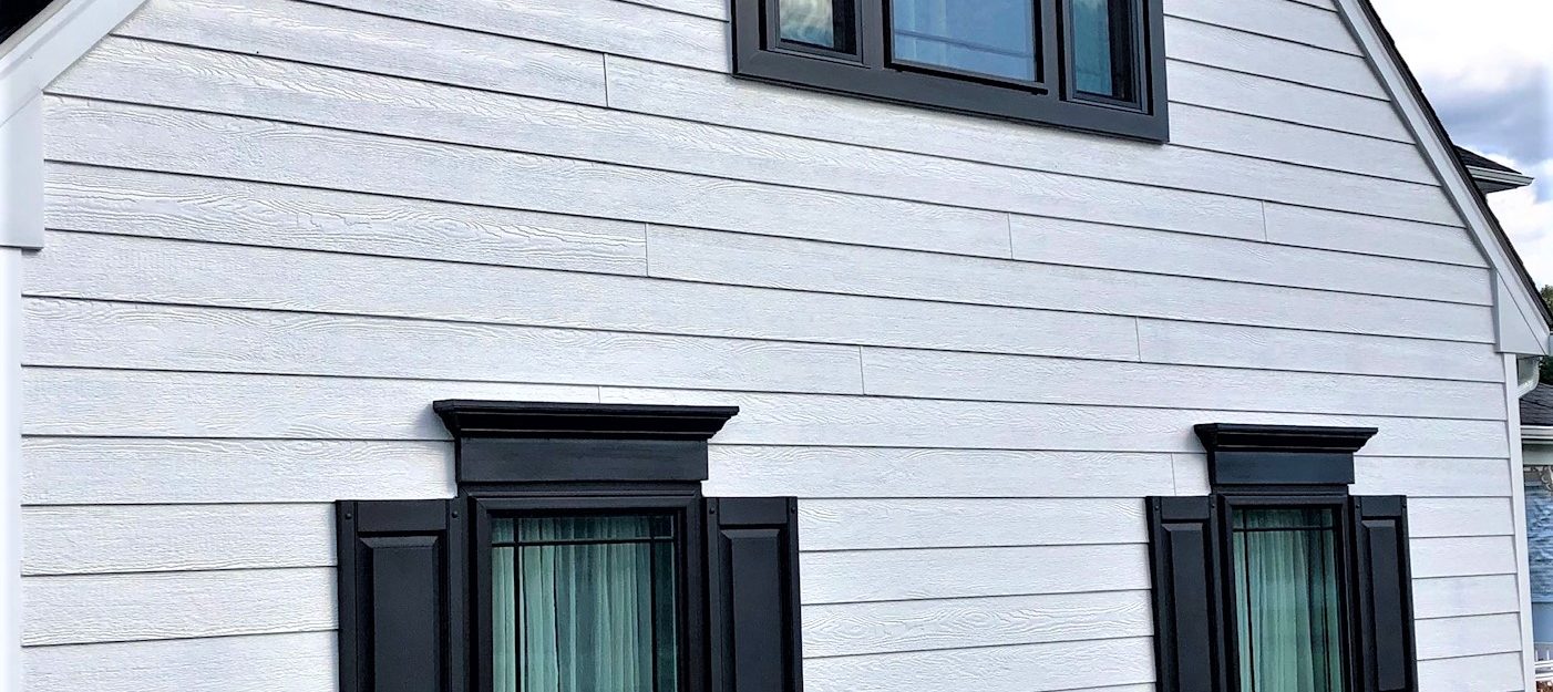 Side view of house with white siding and black windows with black shutters