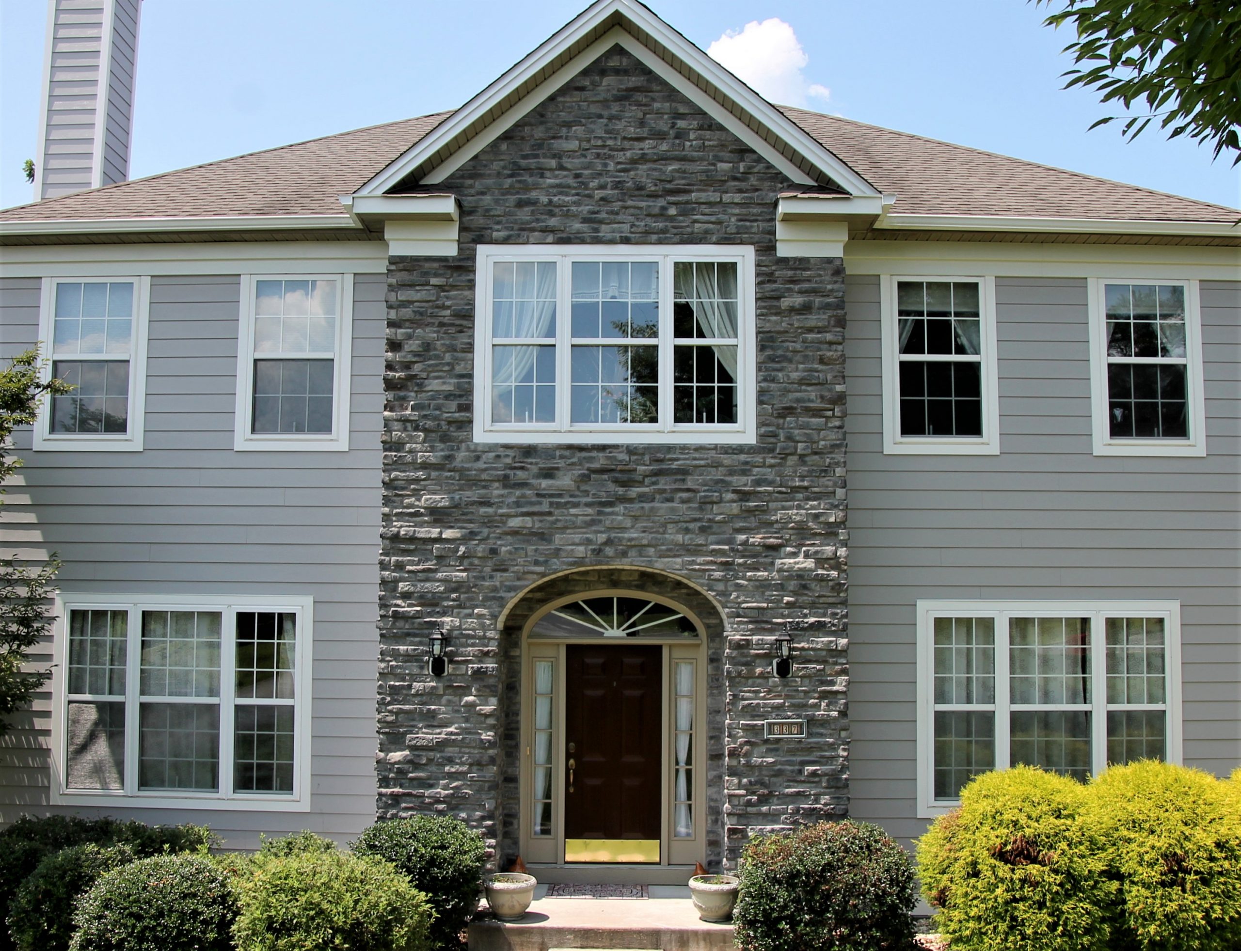 Home exterior with stone veneer and gray siding