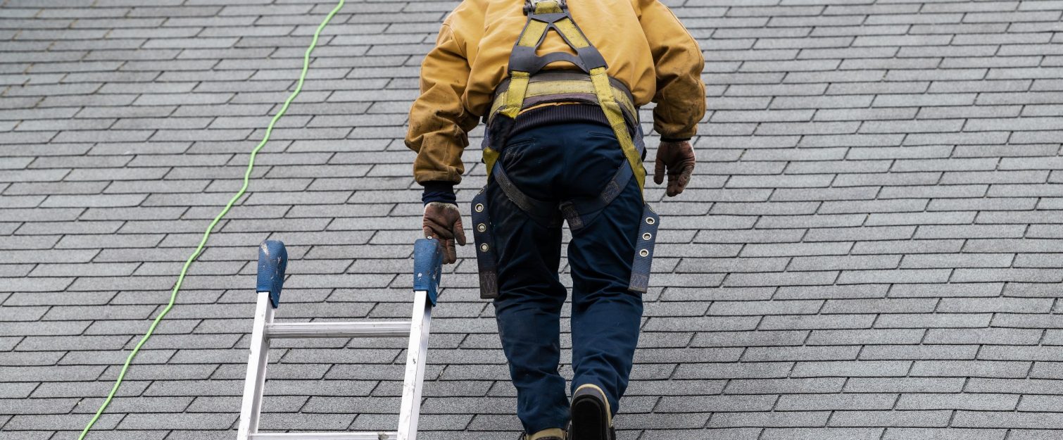 Man on shingle roof performing inspection