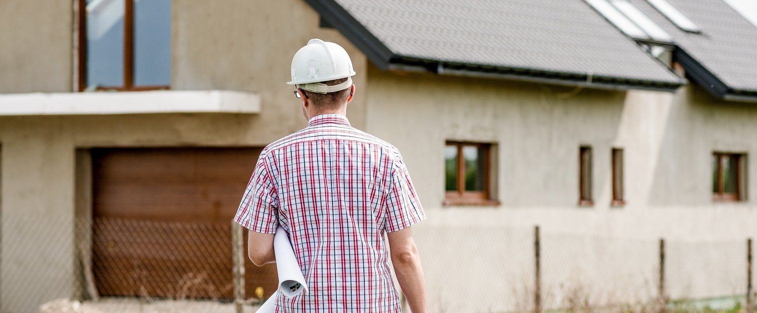 Man with hard hat facing house