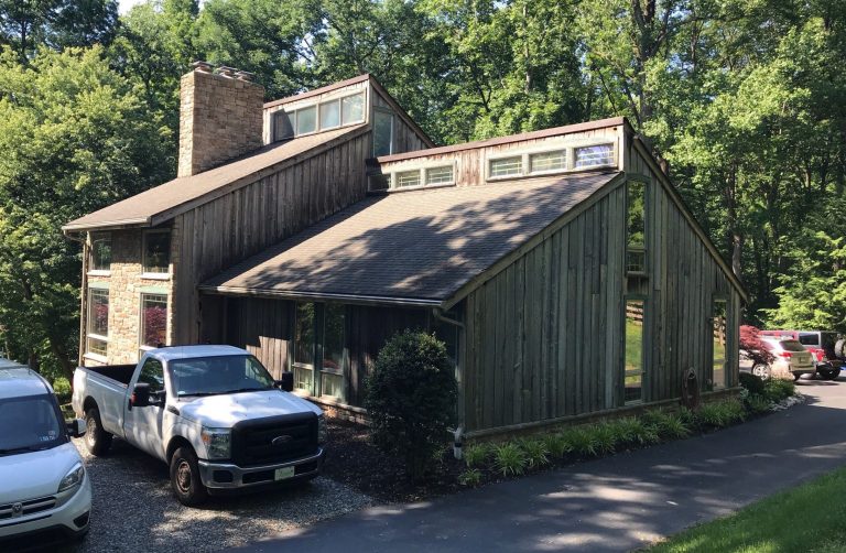 Home exterior before renovation with extremely aged brown cedar siding, old windows fogged from insulation damage, and an old brown roof.