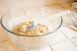 Photo of mixing bowl with batter and spatula inside sitting on a light colored tile counter.